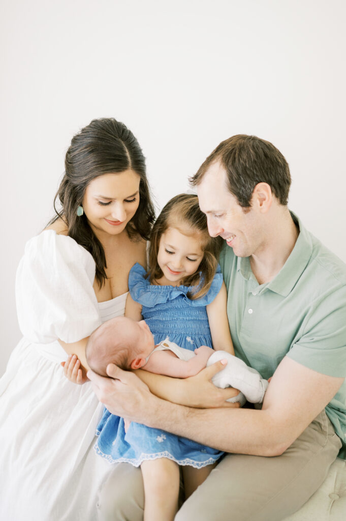 Parents and big sister cradle newborn baby brother during studio newborn session with Worth Capturing