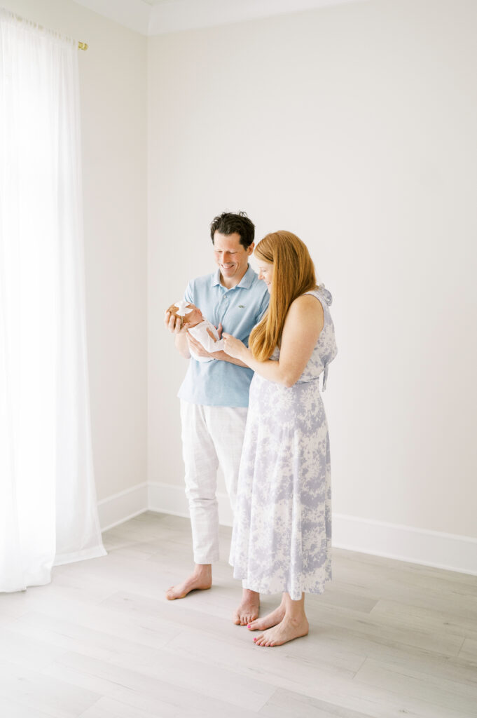 Mom and Dad hold newborn baby girl in the Worth Capturing studio in Raleigh during newborn photos