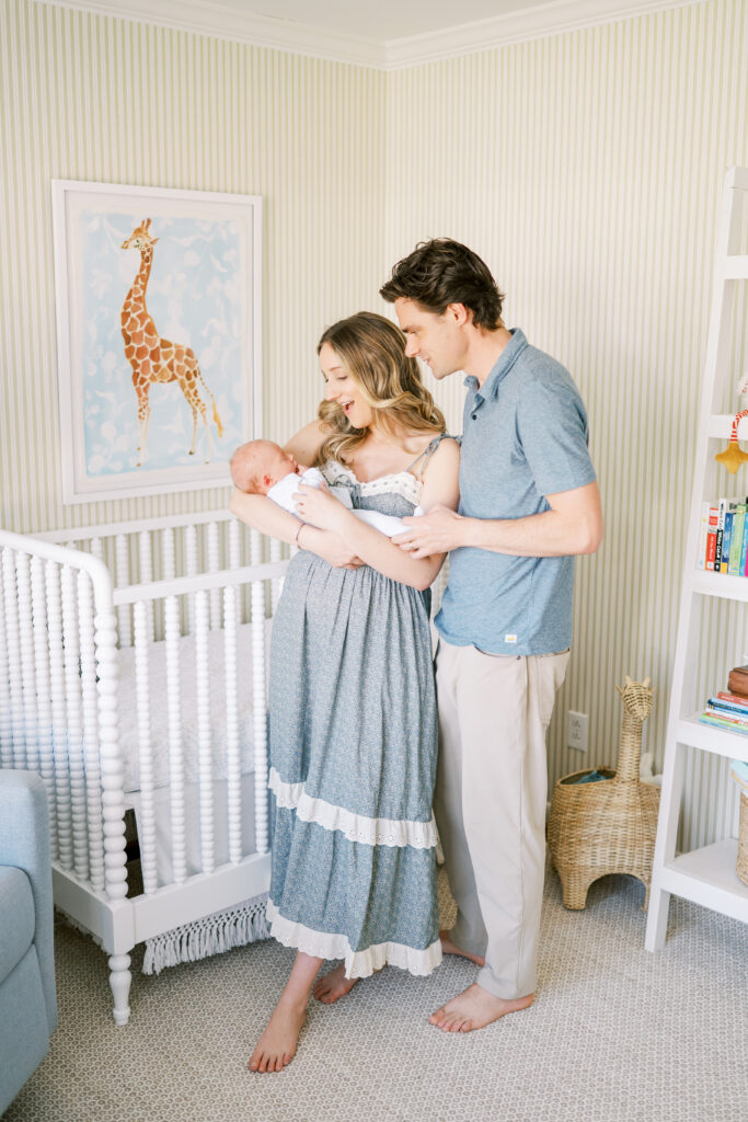 New parents hold newborn baby boy in beautiful nursery during in-home newborn photos in Raleigh