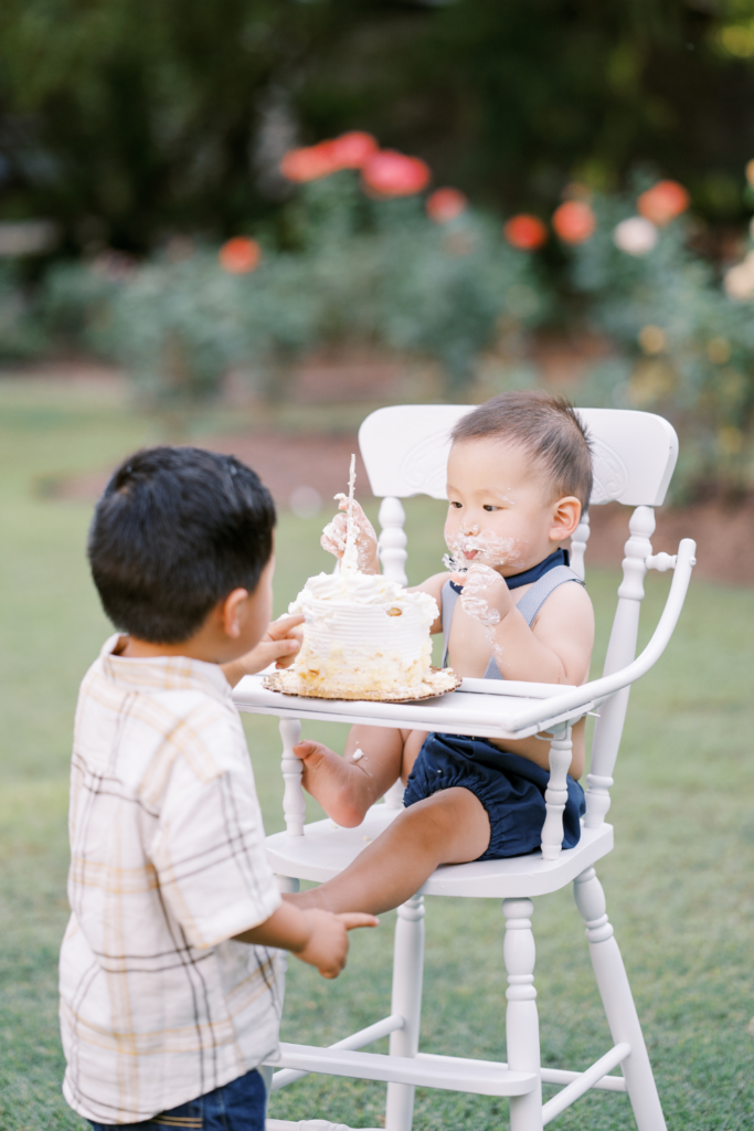 Big brother tastes baby brother's cake during first birthday photo session