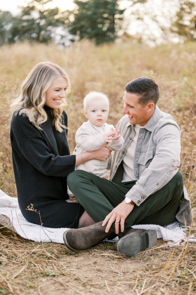 Family of three sit on blanket together during family session in Raleigh with Worth Capturing Photography