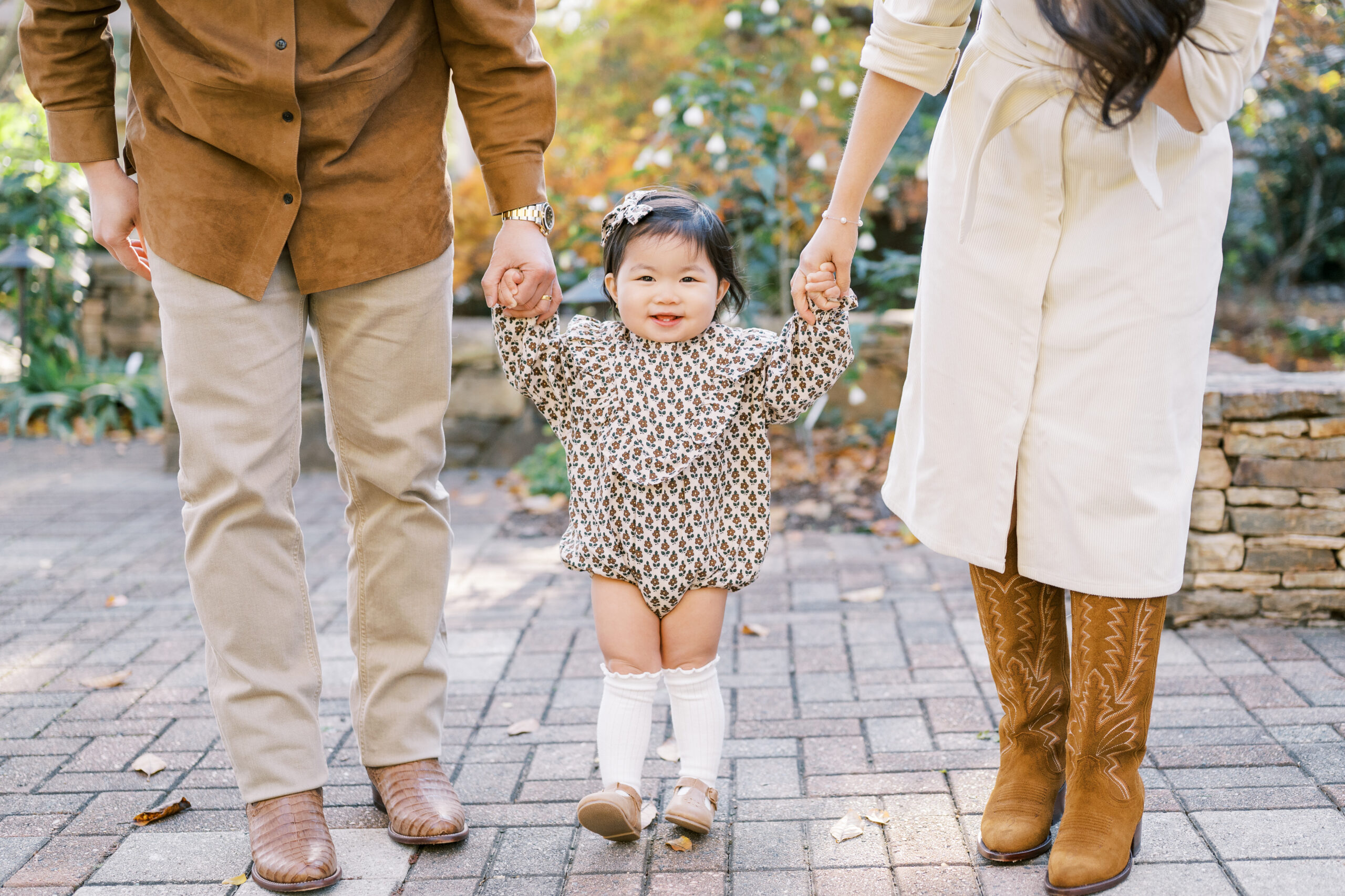 One year old little girl holds parents' hands during fall family photos in Raleigh, NC.